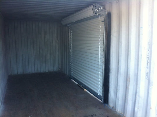 Interior view of a shipping container with a light duty steel roll up door installed for easy access.