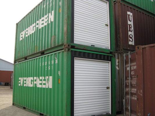 Green shipping containers with white roll up steel doors installed for easy access and secure storage usage