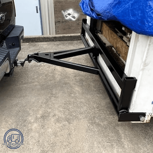 Shipping container tow bar hitch kit attached between truck and container for safe off-road transport.