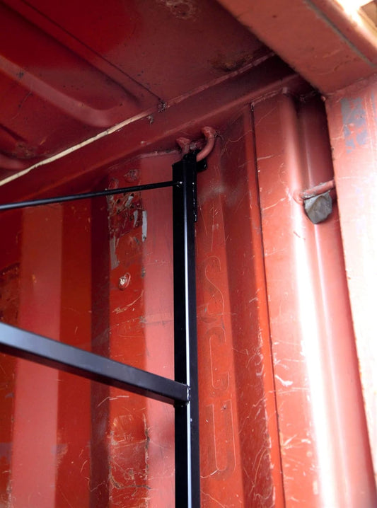 Close-up of black powder-coated steel shelving bracket installed inside a red shipping container wall.